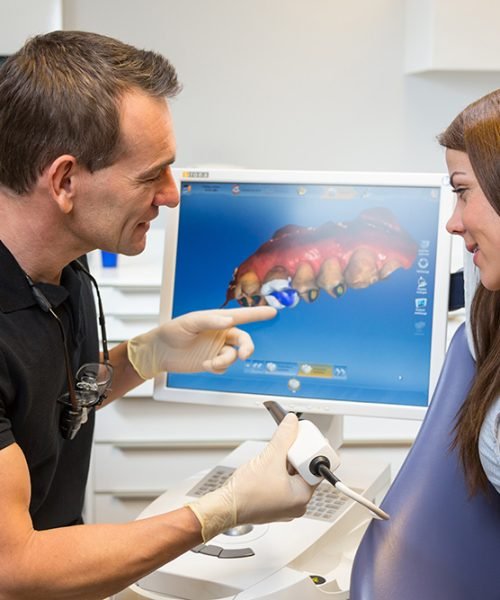 Dentist counseling patient about CEREC (Chairside Economical Restoration of Esthetic Ceramics) dental technology