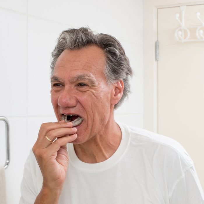 Man Putting in his Night Guard in Front of a Mirror